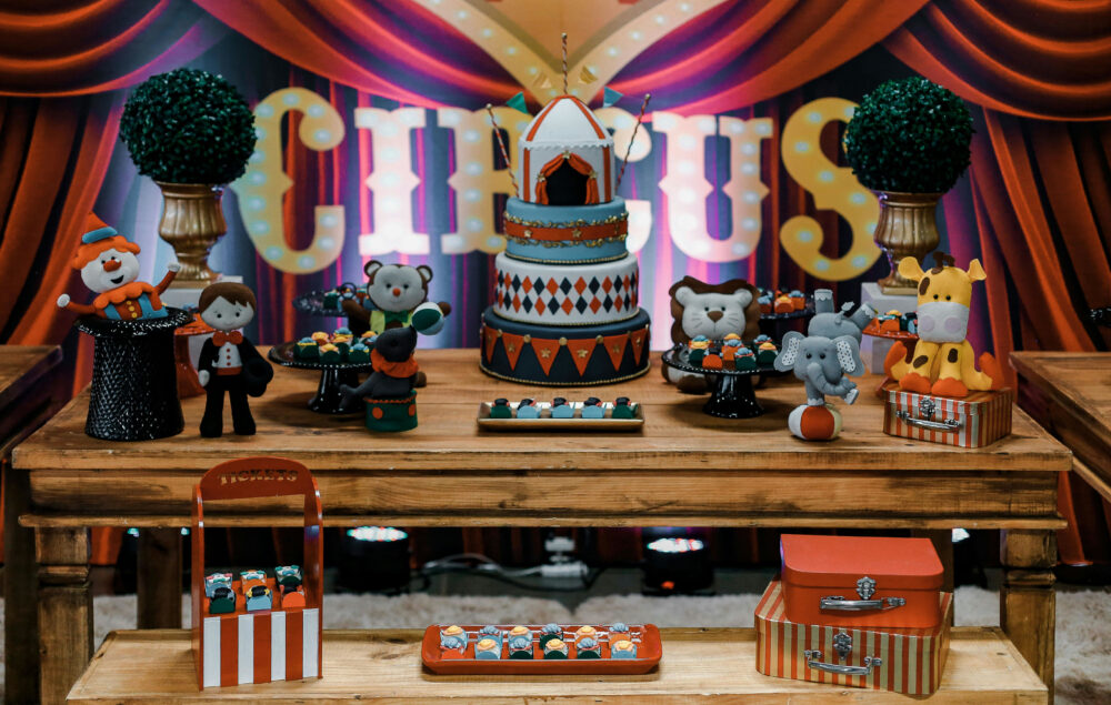 una mesa con objetos que hacen referencia al circo como muñecos de magos y animales, carpas y la palabra Circus escrita en grande